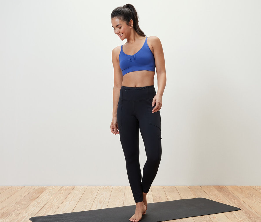 Frau steht auf einer Yogamatte und trägt ein Seamless-Sport-Bustier.