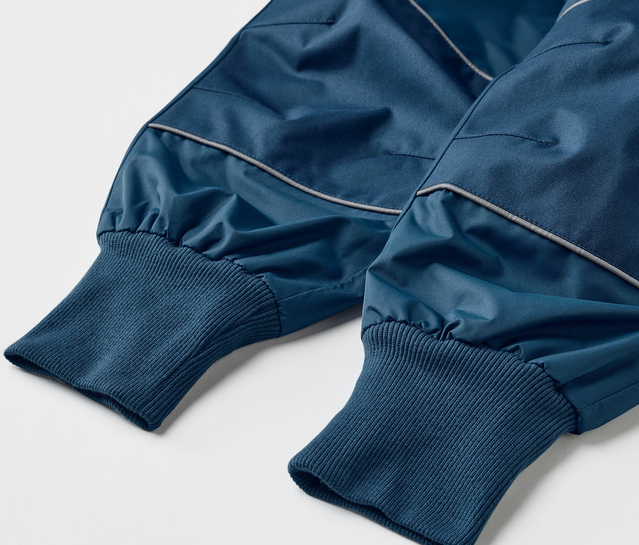Detailaufnahme einer blauen Kinder-Regenhose mit Mitwachsfunktion.
