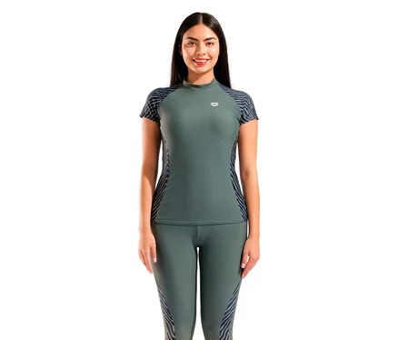 Eine lächelnde Frau trägt ein dunkelgrünes arena Damen-UV-Schutz-Rash-Allover-Kurzarm-Schwimmshirt mit gemusterten Ärmeln und Seiten, dazu passende Leggings.