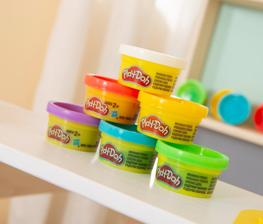 Ein Stapel aus sieben bunten Play-Doh-Dosen steht auf einem Regal.