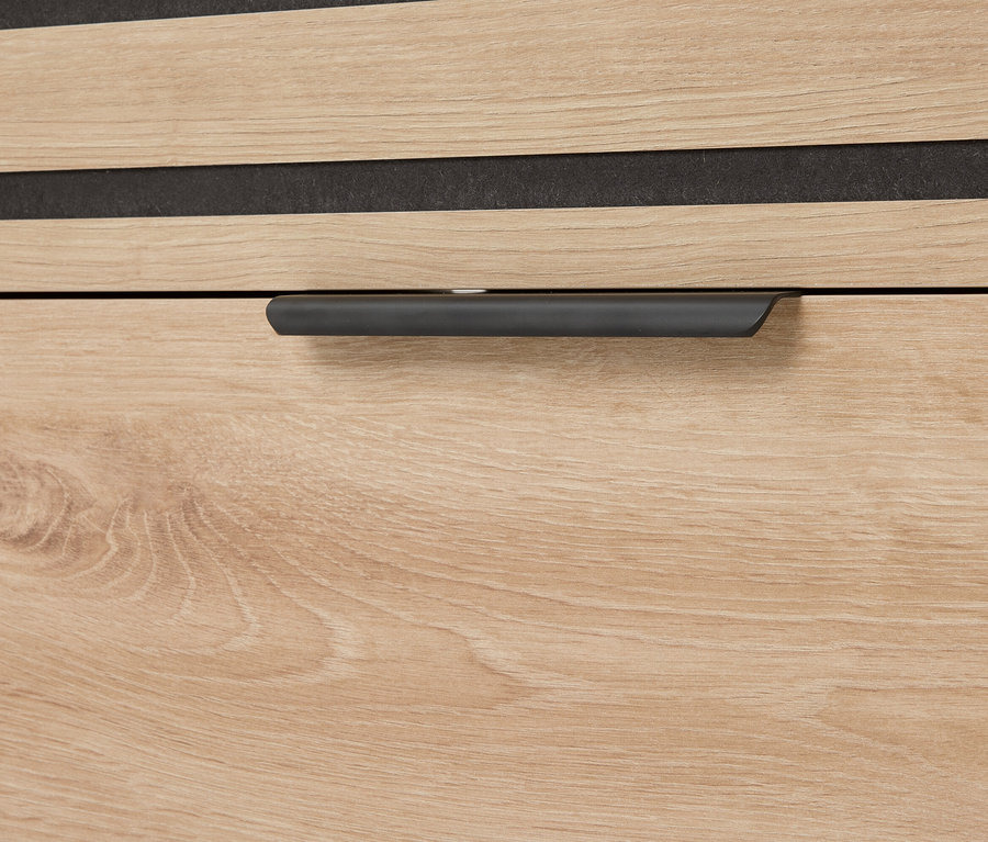 Nahaufnahme einer Schublade mit Holzmaserung und einem grauen Griff.