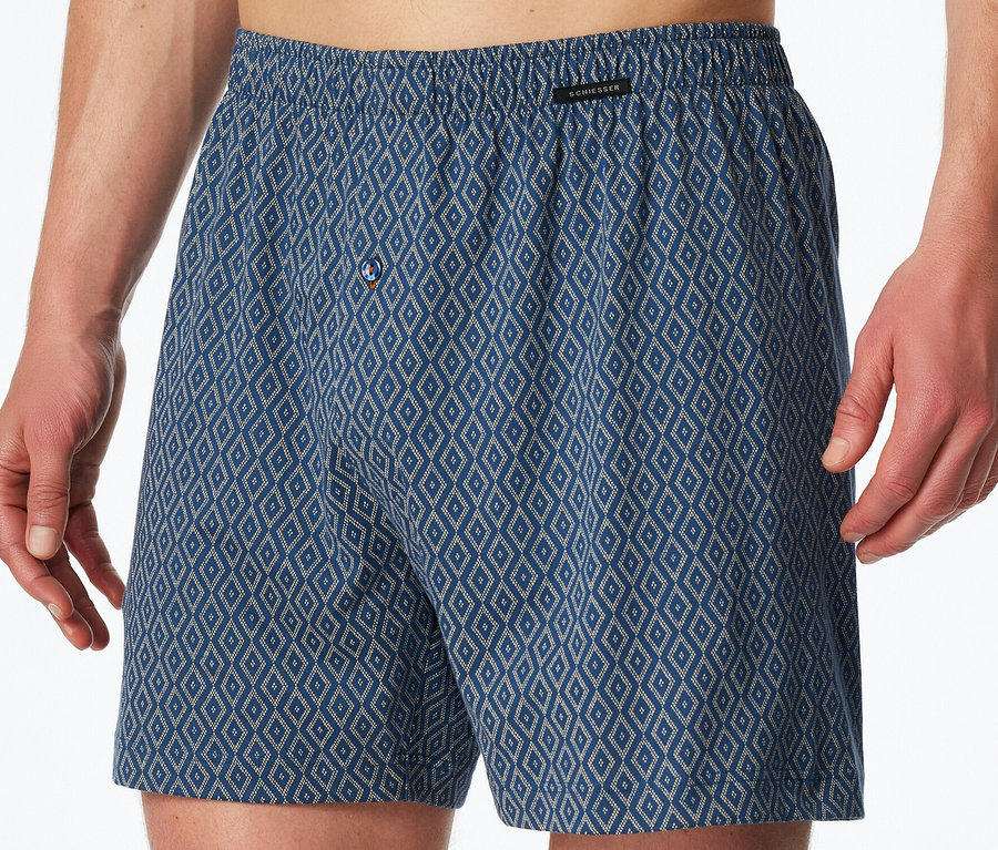 Mann trägt blaue SCHIESSER Jersey-Boxer mit Rautenmuster und Knopfverschluss.