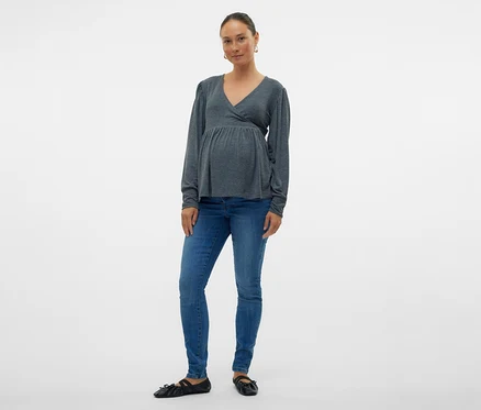 Frau in grauer Wickelbluse und MAMALICIOUS Skinnyjeans »MLMILA«, posiert vor weißem Hintergrund.