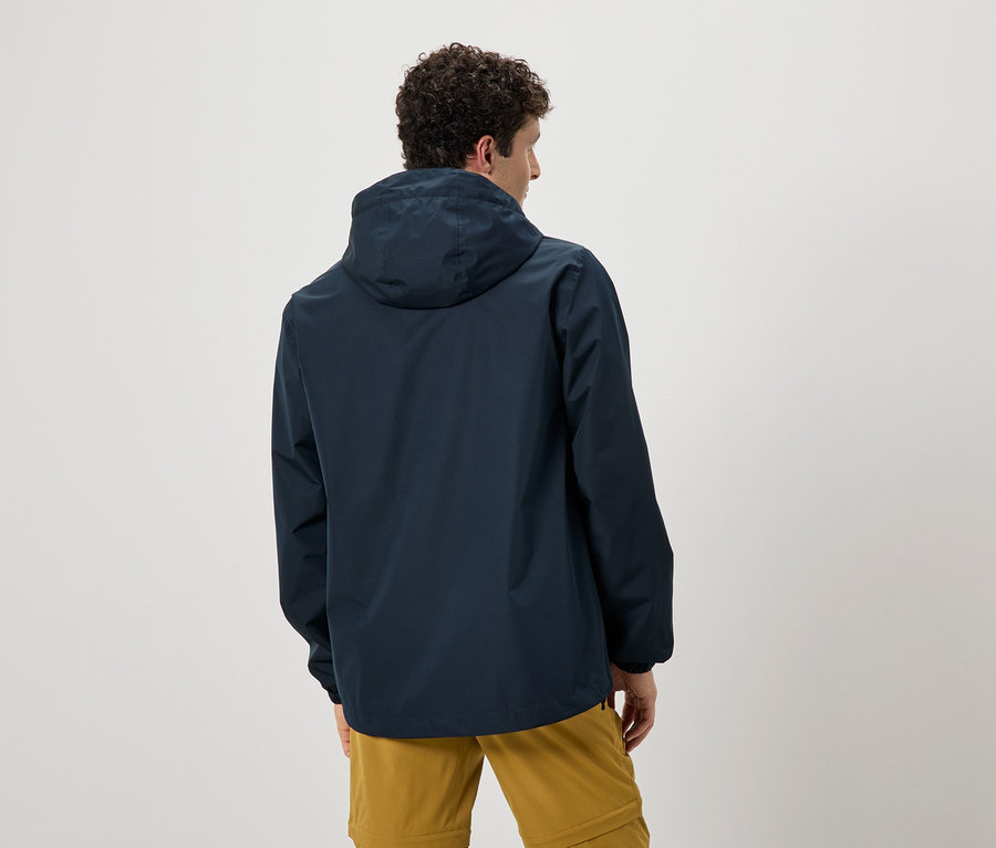 Rückansicht eines Mannes mit lockigem Haar, der eine marineblaue Regenjacke mit Kapuze und ockerfarbene Hosen trägt.