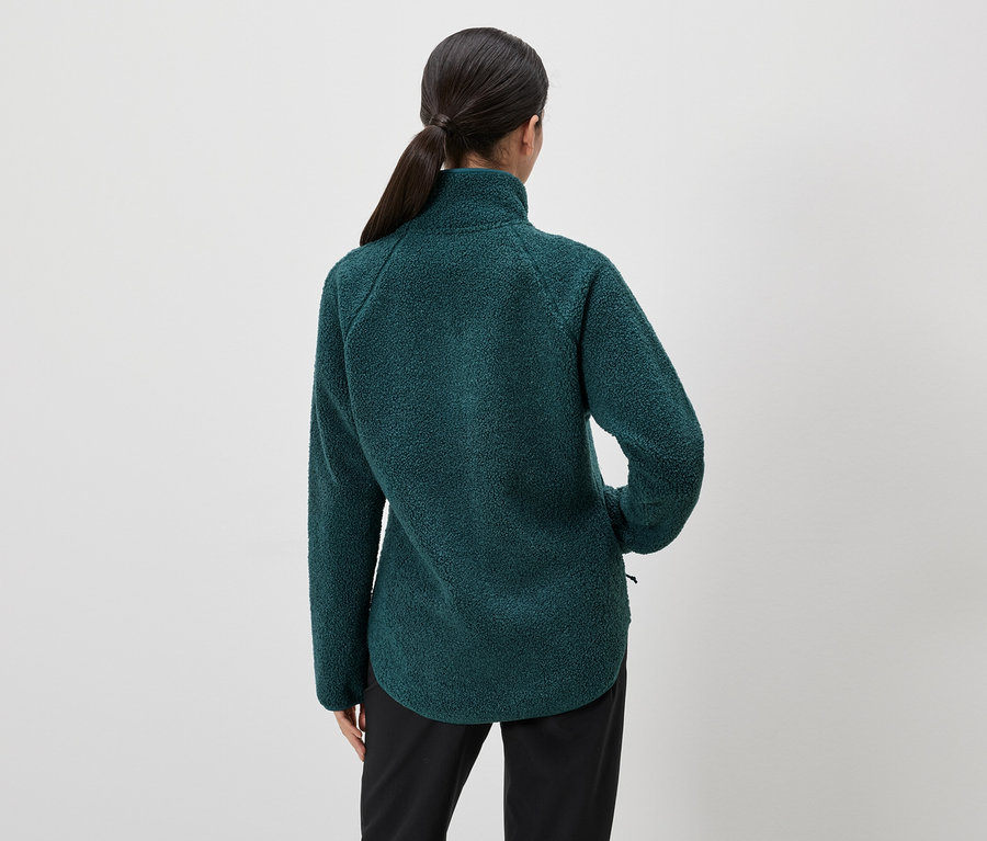 Rückansicht einer Frau mit Pferdeschwanz, die eine grüne Fleecejacke und schwarze Hose trägt.