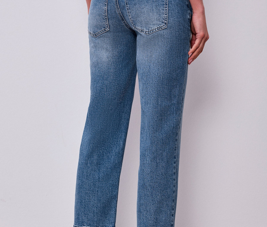 Eine Person trägt hellblaue Street One Jeans mit ausgefransten Säumen und dunkelbraune Loafer.