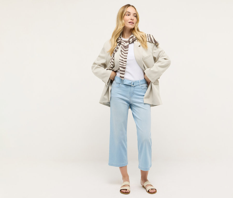 Eine Frau steht und trägt Angels Denim »Linn City« cropped, bleached blue, ein weißes T-Shirt, einen Blazer und einen Schal.