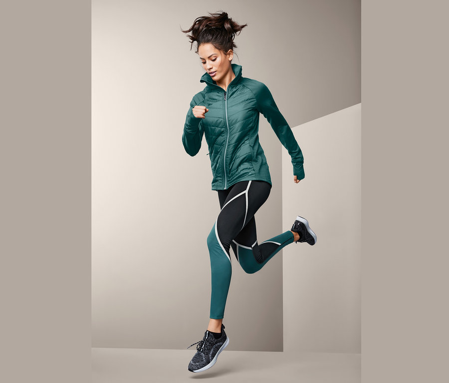 Frau läuft in Sporttight und Jacke.