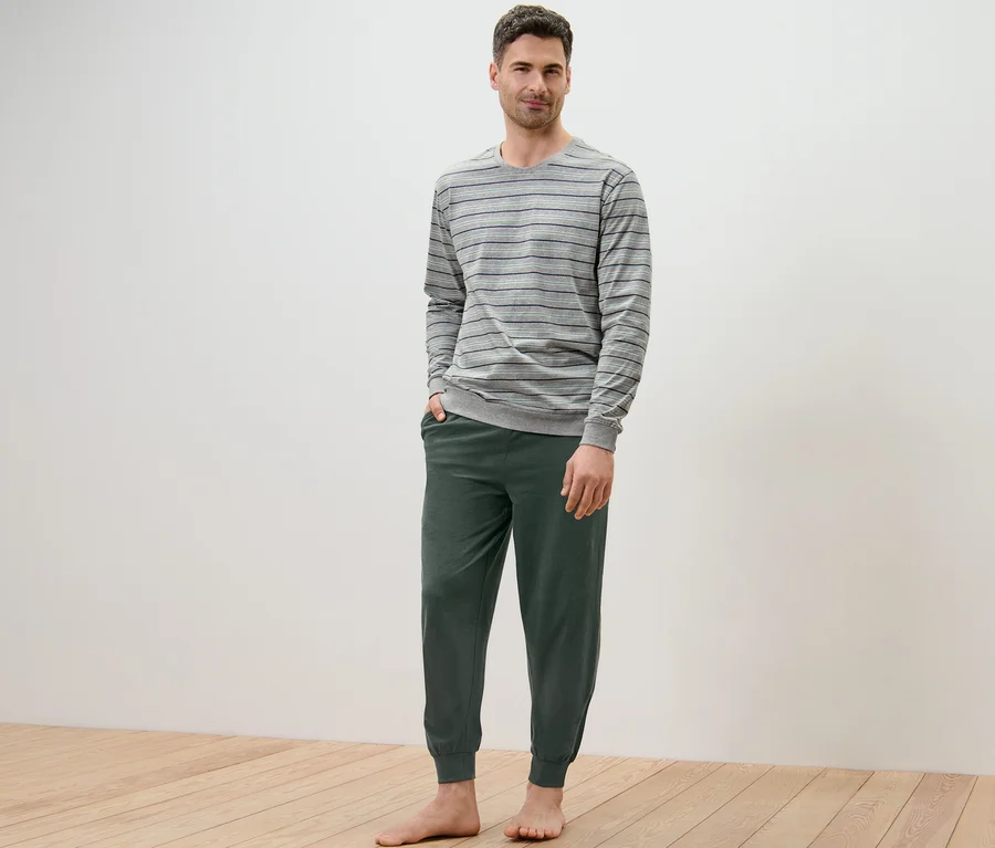 Mann steht barfuß und trägt einen grün gestreiften Pyjama.