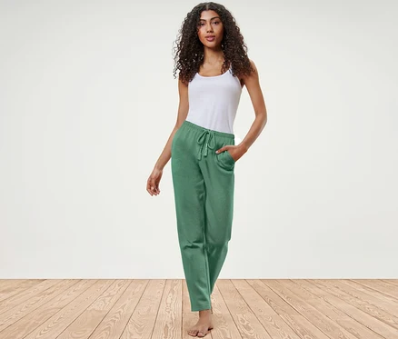 Frau posiert in grüner Loungewear-Hose und weißem Top.