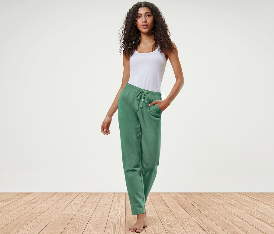 Frau posiert in grüner Loungewear-Hose und weißem Top.