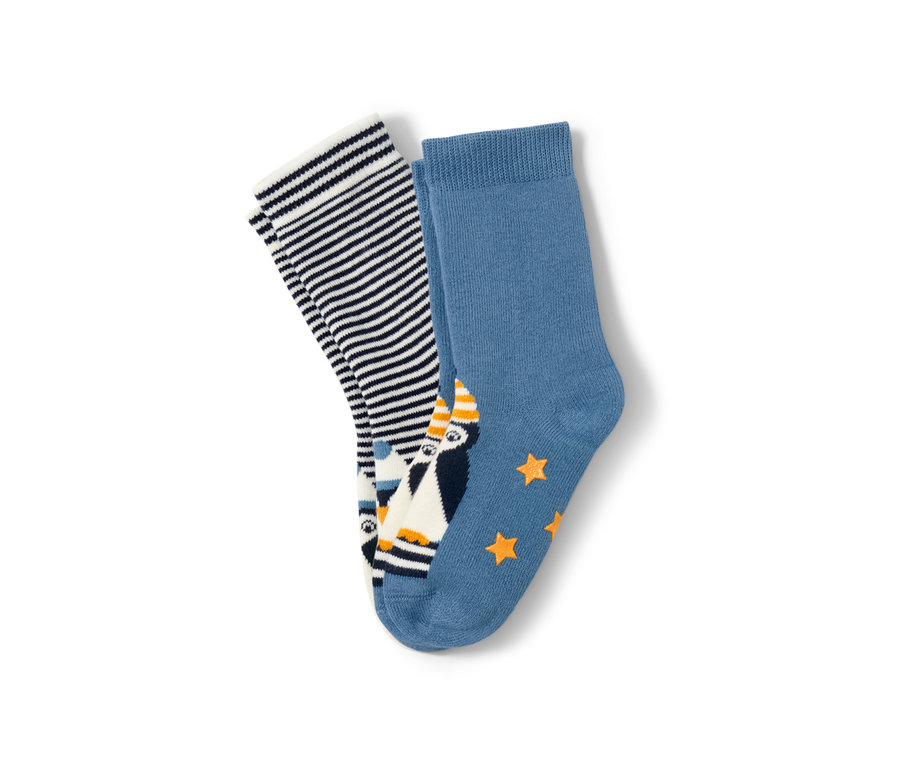 Zwei Paar Kleinkind-Antirutsch-Socken. Ein Paar ist blau mit Pinguin und Sternen, das andere mit blau-weissen Streifen.