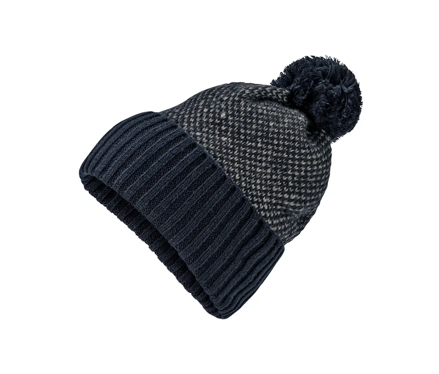 Detailaufnahme einer dunkelblau-beigen Strickmütze mit Bommel auf weißem Hintergrund.