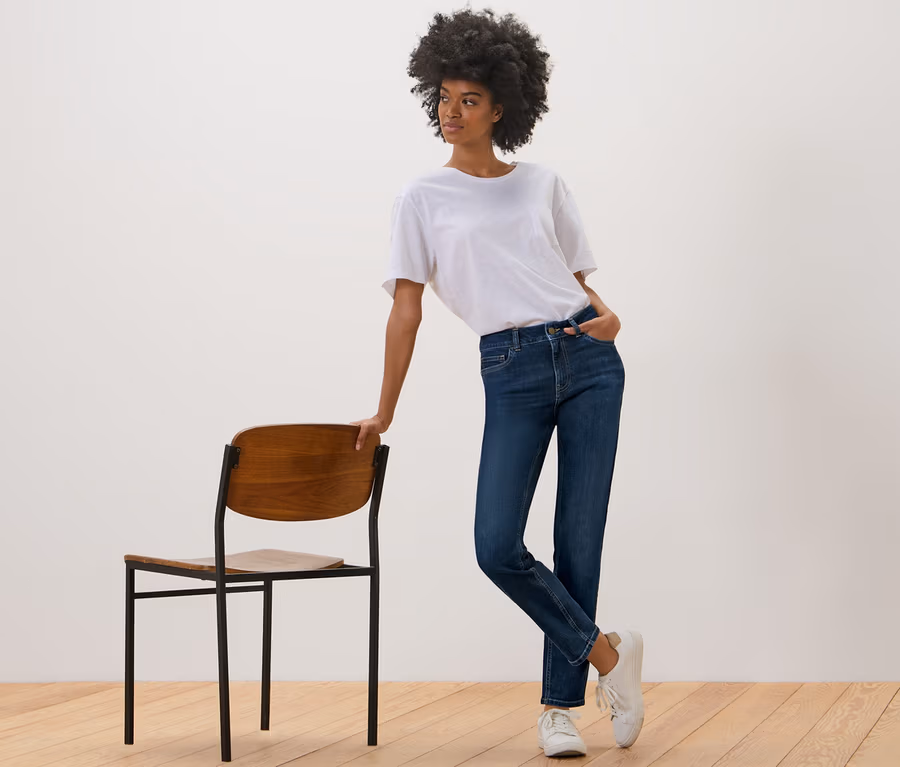 Frau posiert neben einem Stuhl und trägt eine dunkelblaue Slim Jeans – Fit »Emma«.