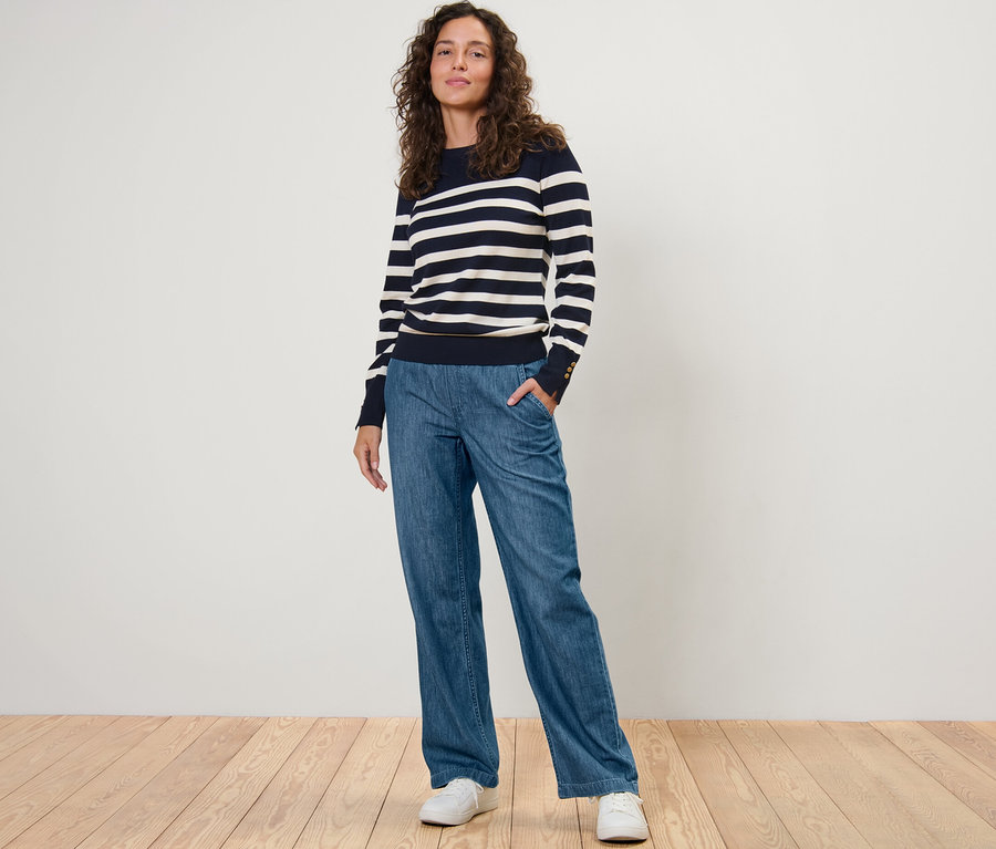Eine Frau posiert in Wide-Comfort-Jeans und einem gestreiften Pullover.
