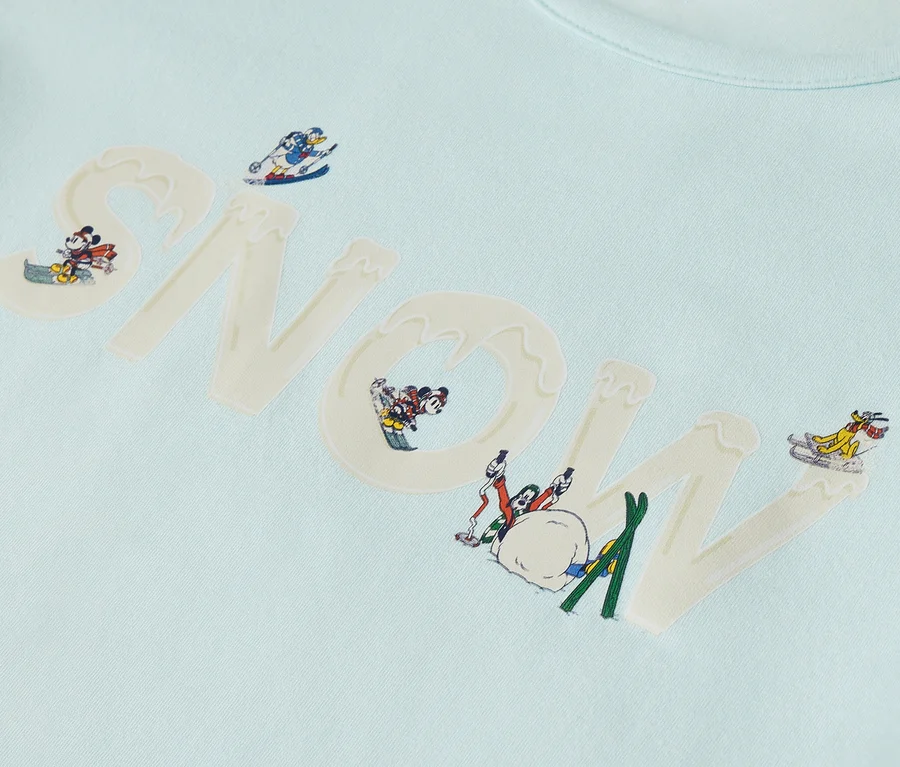 Hellblaues T-Shirt mit dem Wort "SNOW" und Zeichentrickfiguren in Winterszenen.
