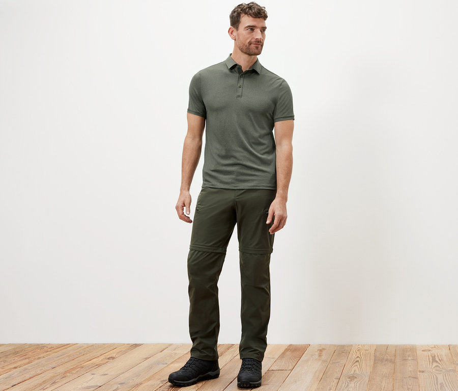 Mann steht und trägt ein khaki Funktions-Poloshirt.