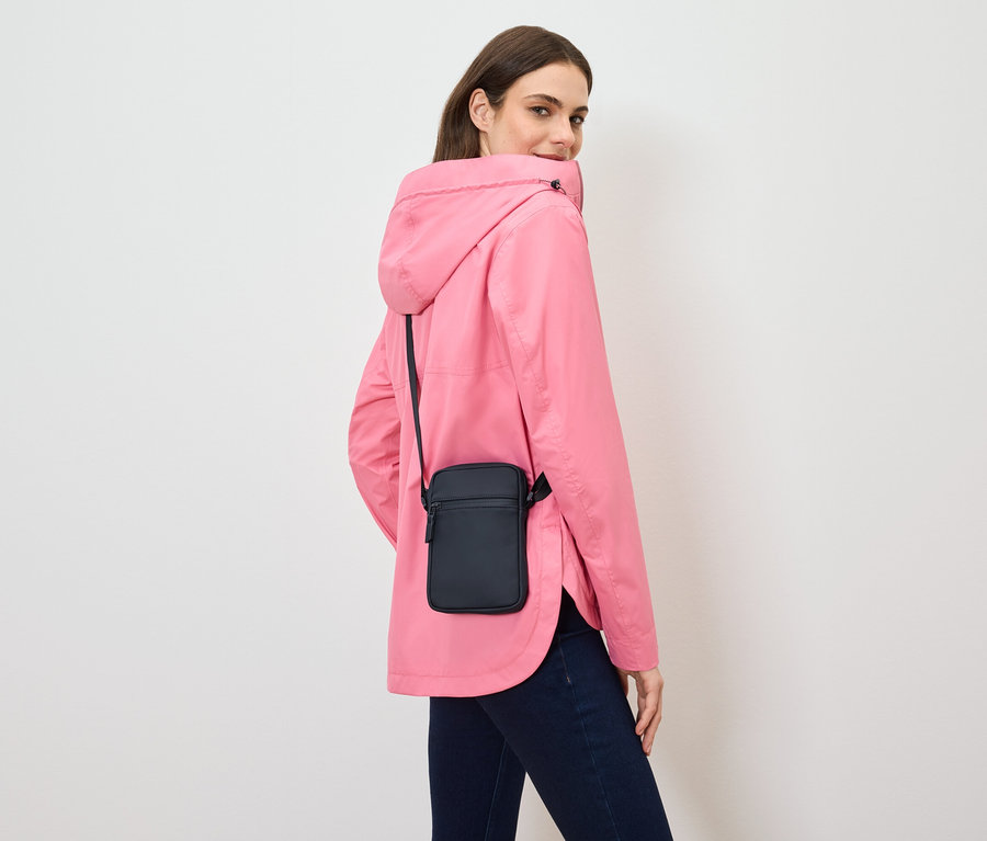 Eine Frau blickt über ihre Schulter und trägt eine rosa Jacke und eine schwarze Umhängetasche.