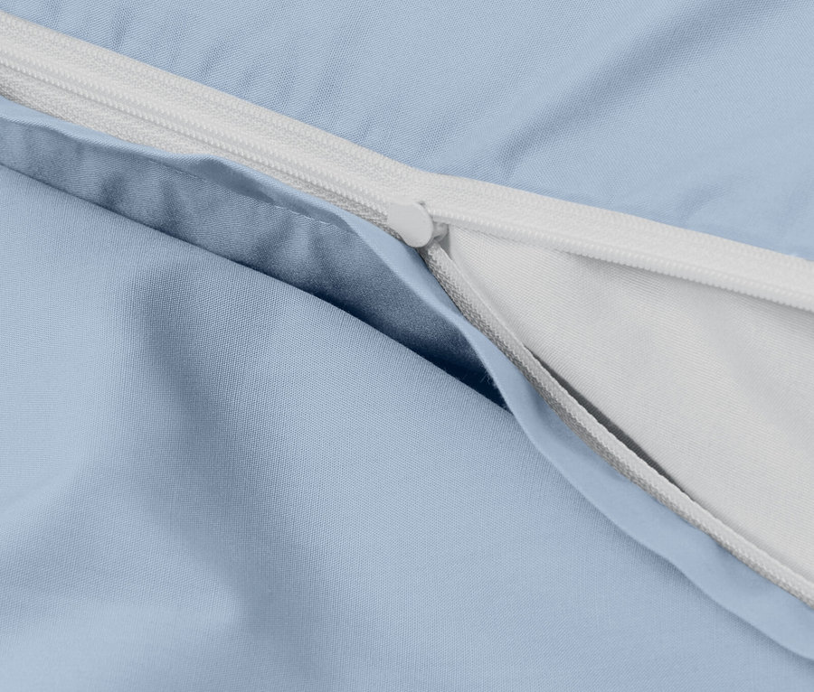 Detailaufnahme eines hellblauen Bettbezugs mit weißem Reißverschluss.
