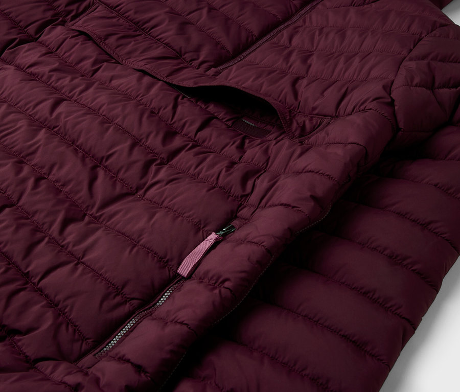 Detailaufnahme einer bordeauxroten Steppjacke mit Reißverschluss und Tasche.
