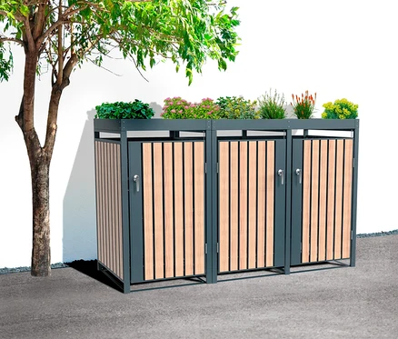 Drei Mülltonnenboxen mit Blumenkästen auf der Oberseite und einem Baum daneben.