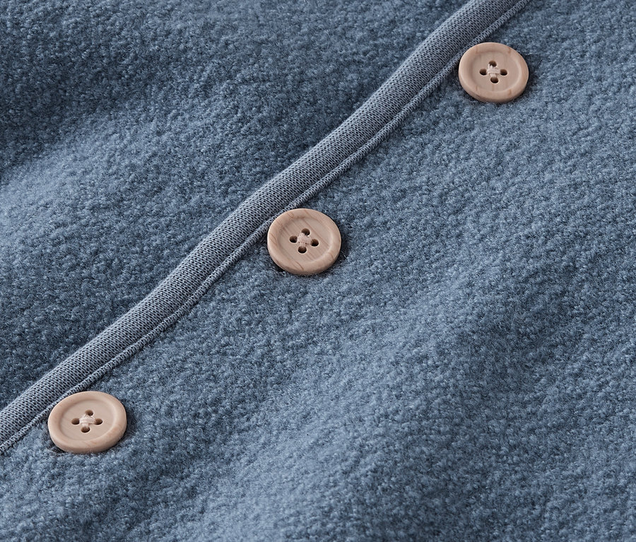 Detailaufnahme eines blauen Pullovers mit braunen Knöpfen.