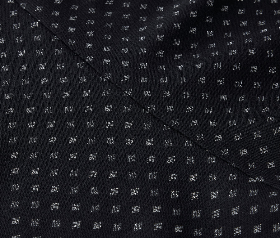 Detailaufnahme eines schwarzen Stoffes mit einem regelmäßigen Muster aus kleinen weißen Quadraten und einer diagonalen Naht.