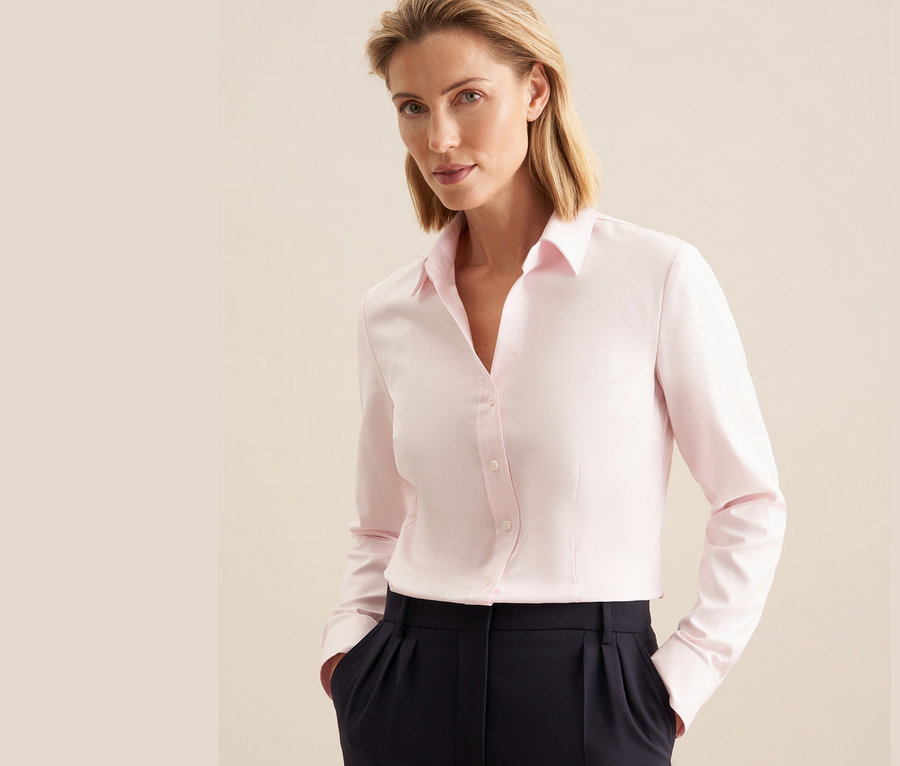 Frau trägt eine roséfarbene Seidensticker Twillbluse und eine marineblaue Hose.