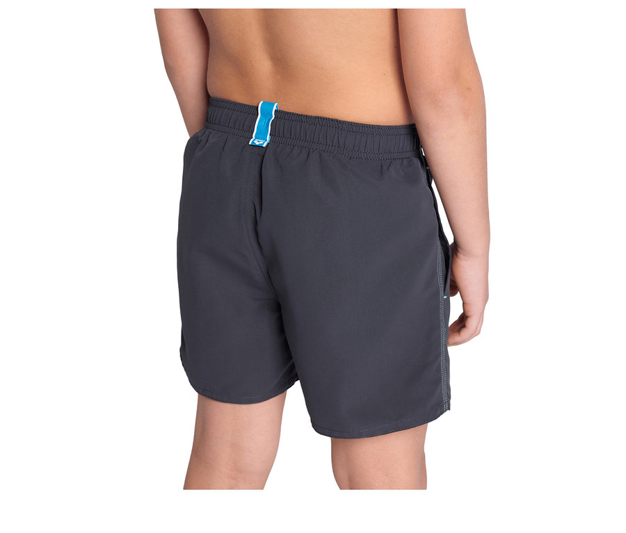 Rückenansicht eines Kindes, das eine schwarze arena Kinder-Beach Boxer Solid R mit blauem Bundetikett trägt.