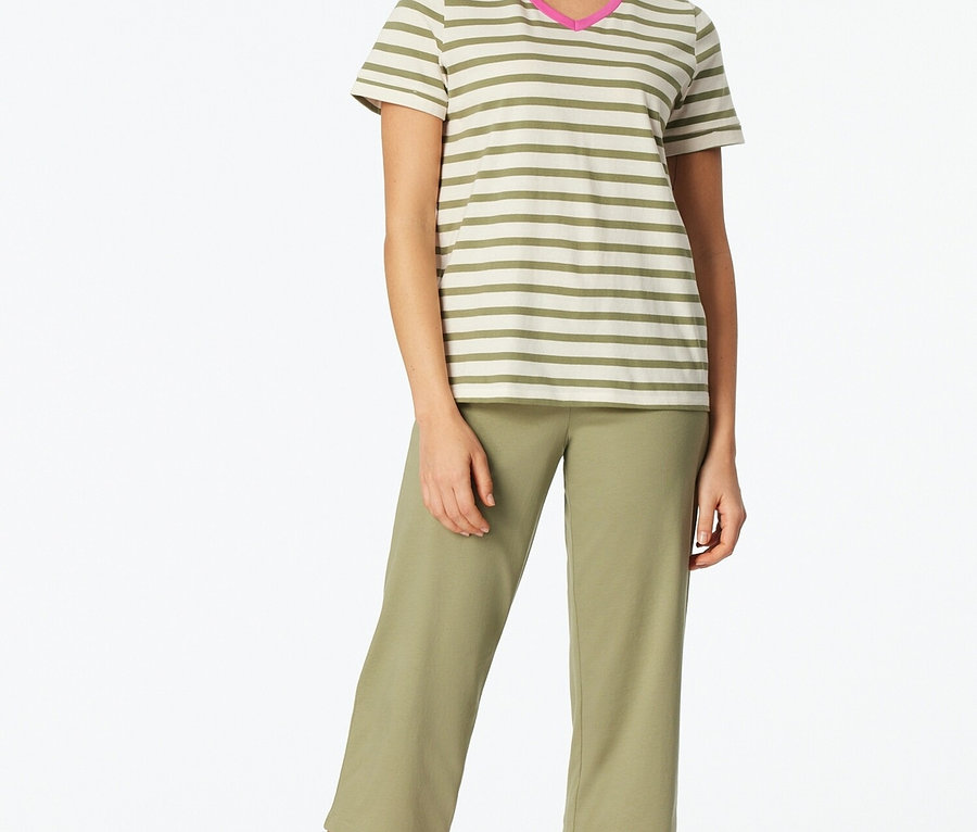 Frau steht barfuß, trägt ein gestreiftes T-Shirt mit pinkem Ausschnitt und olivfarbene Dreiviertelhosen.