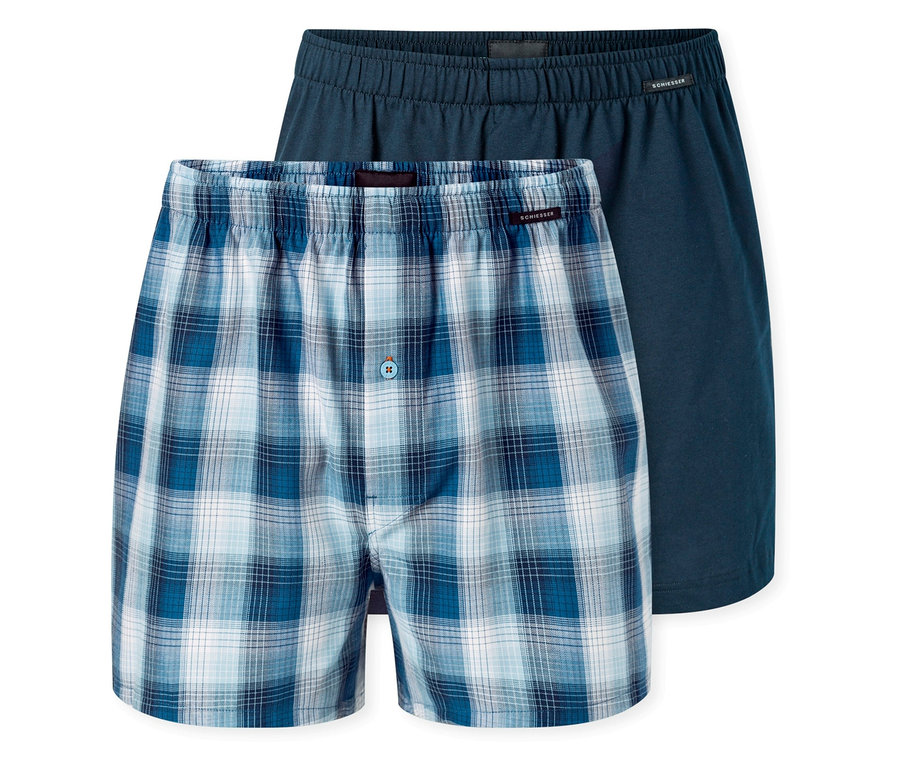 Zwei SCHIESSER Web-Boxer. Einer ist blau-weiß kariert mit Knopf, der andere ist einfarbig dunkelblau.