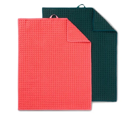Ein korallenfarbenes Tuch liegt teilweise über einem dunkelgrünen Tuch.