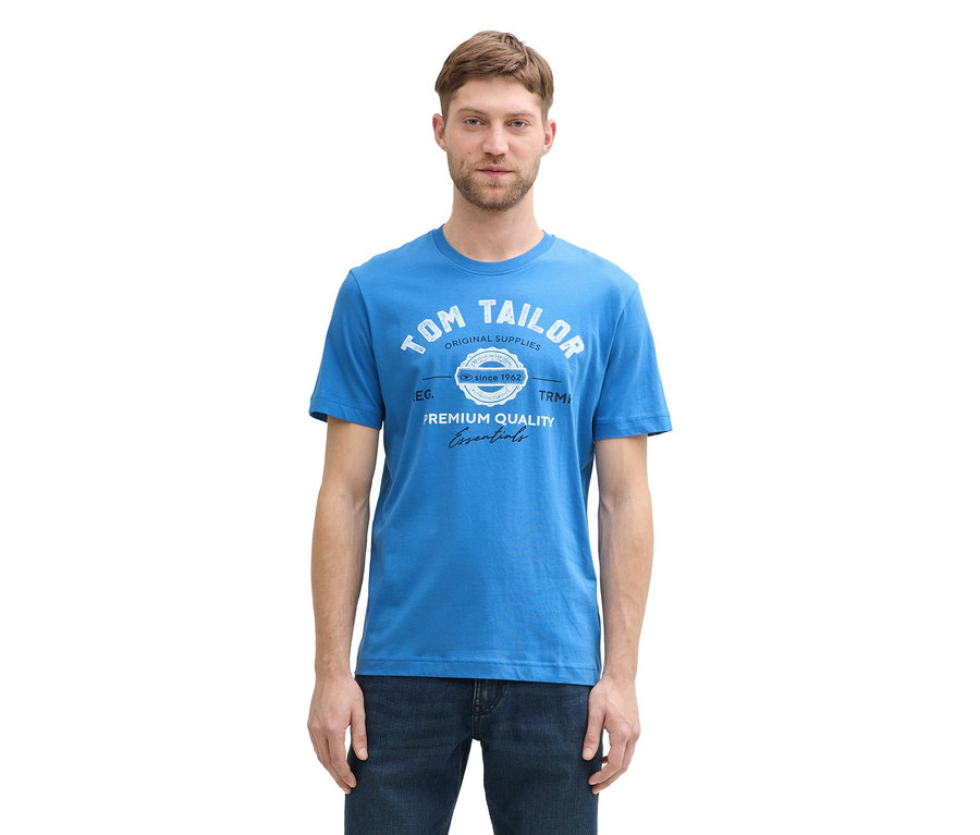 Mann trägt ein Tom Tailor T-Shirt mit Logo in Saphirblau und Jeans.