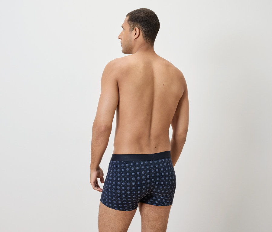 Rückansicht eines Mannes mit dunkelblauen Boxershorts mit Punktmuster.