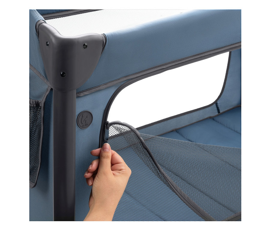 Nahaufnahme einer Hand, die den Reißverschluss an einem blauen Kinderbett mit Netzstoff öffnet.