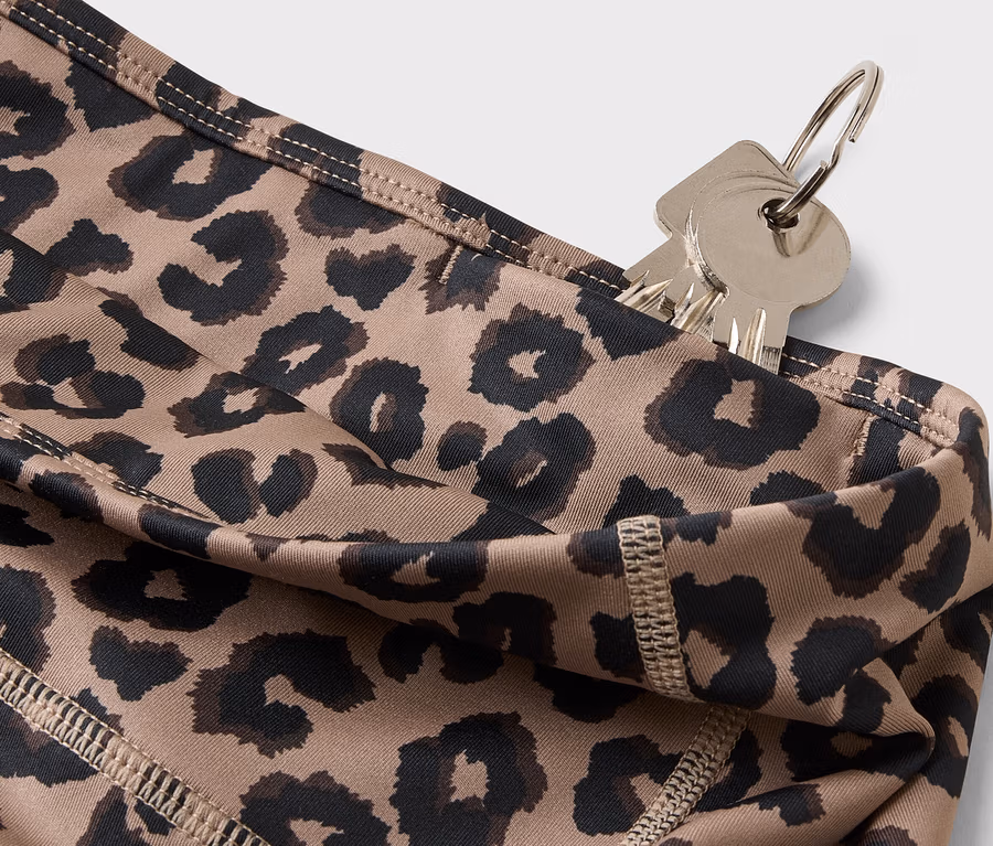 Nahaufnahme von Schlüsseln, die an einem Schlüsselring hängen und in die Tasche einer Leggings mit Leopardenmuster gesteckt wurden.