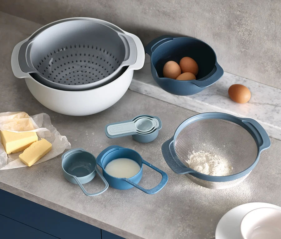 Auf einer Küchentheke stehen der Joseph Joseph Back-Set, 3-teilig, Eier, Milch, Mehl und Butter.