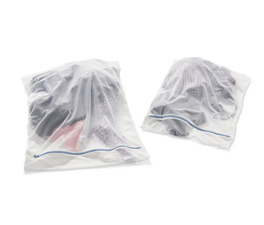 Zwei weiße XL-Wäschenetze, gefüllt mit Kleidung.