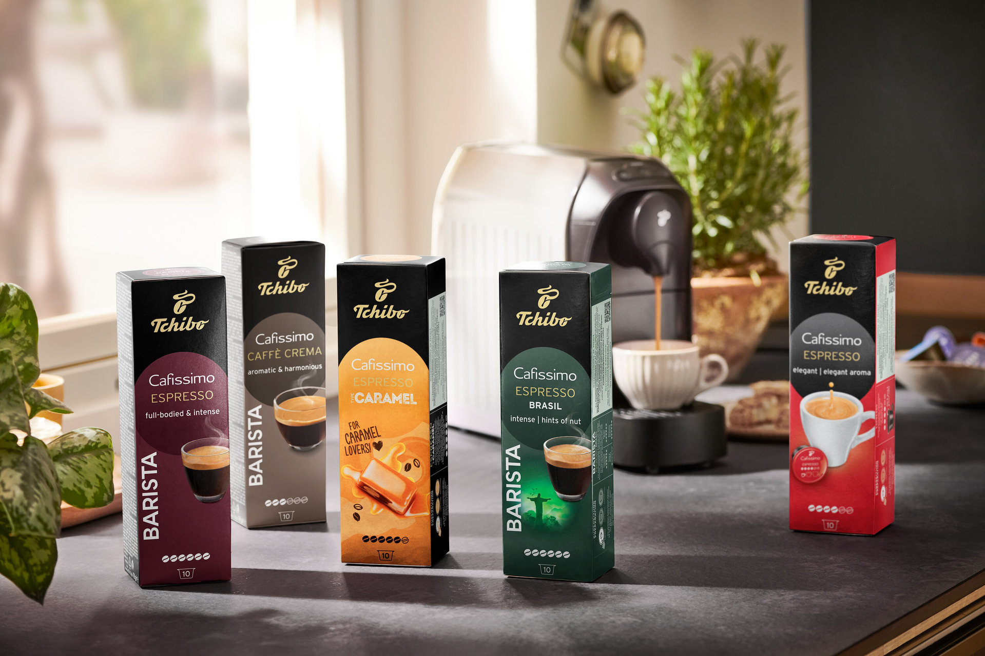 Fünf Packungen Cafissimo BARISTA Espresso Brasil Kapseln und eine Kaffeemaschine. Kaffee fließt aus der Kaffeemaschine in eine Tasse.