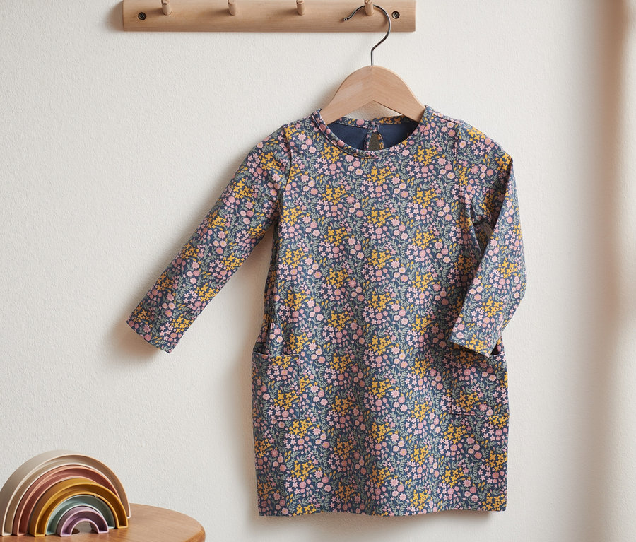 Ein Jerseykleid mit Blumenmuster hängt an einem Kleiderbügel.