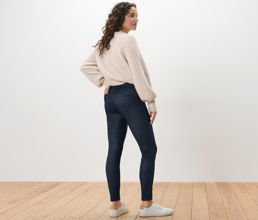Frau posiert in gefütterter Leggings in Jeansoptik und Pullover.