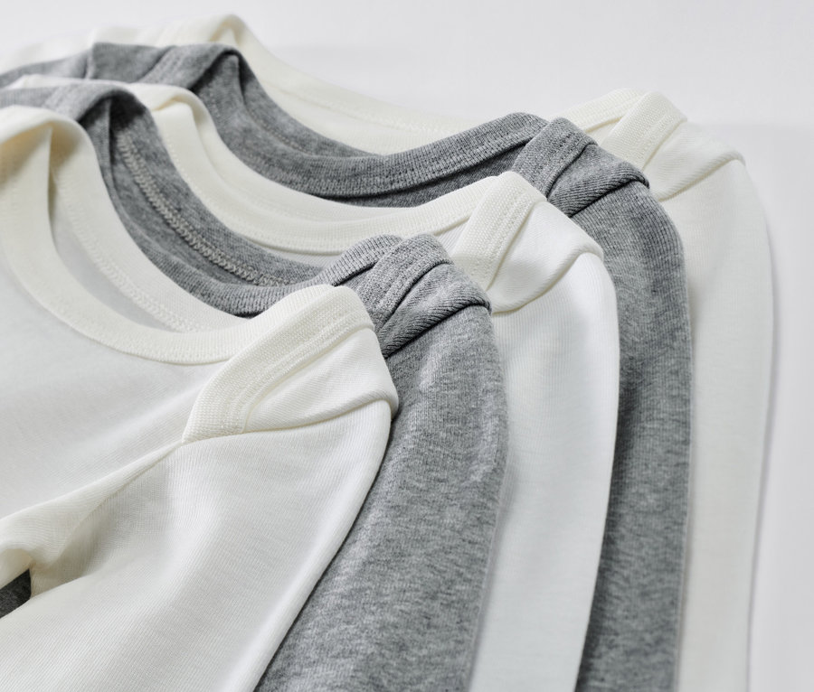 Detailaufnahme von fünf Baby-Langarmbodys in Weiß und Grau.