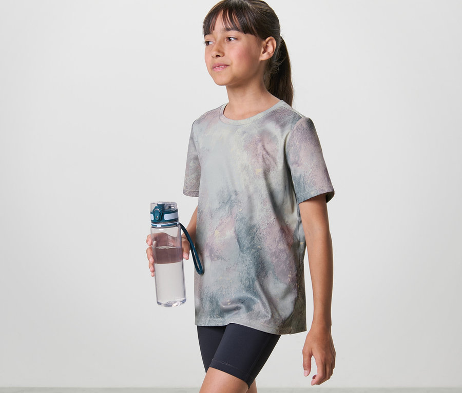 Mädchen mit Trinkflasche trägt ein Kinder-Sportshirt (2 Stk).