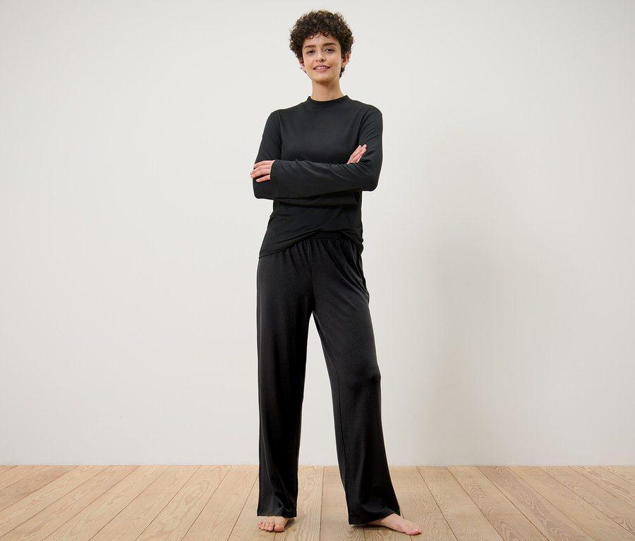 Frau steht mit verschränkten Armen da und trägt eine weite Sporthose.