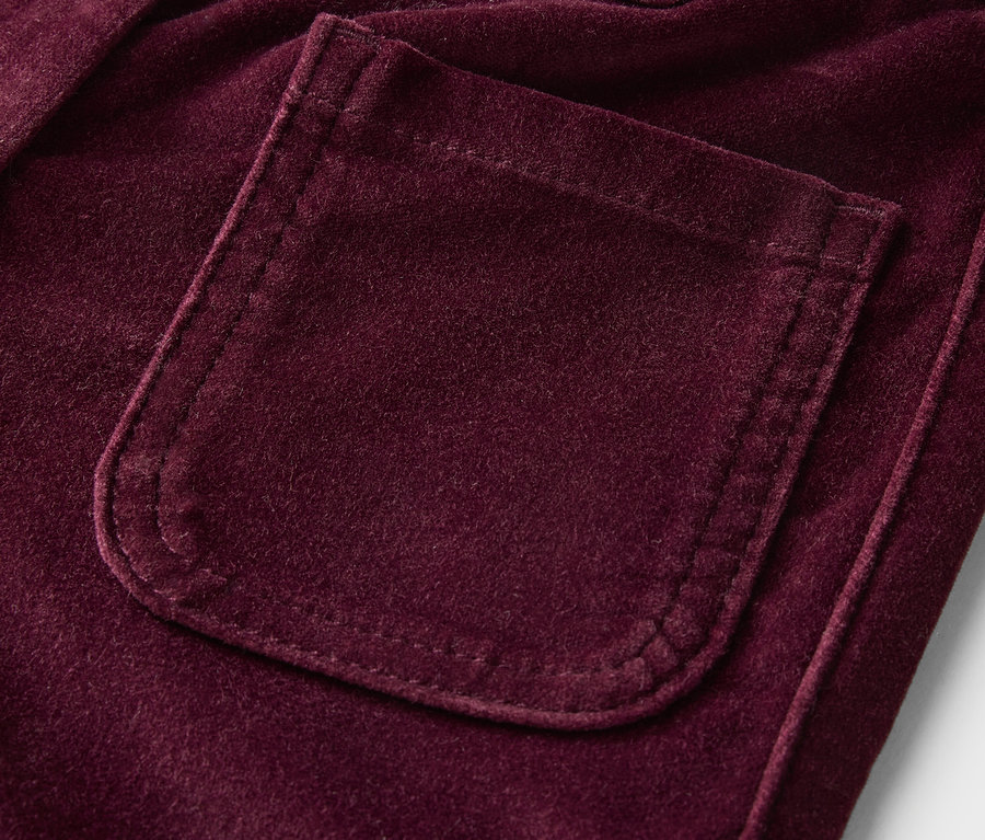 Detailaufnahme einer lilafarbenen Samthose mit Tasche.