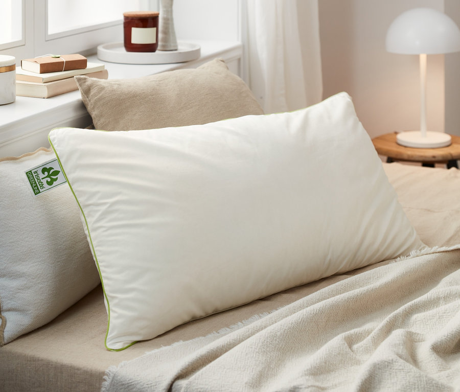 Mehrere irisette® greenline Federkopfkissen in verschiedenen Größen liegen auf einem Bett.