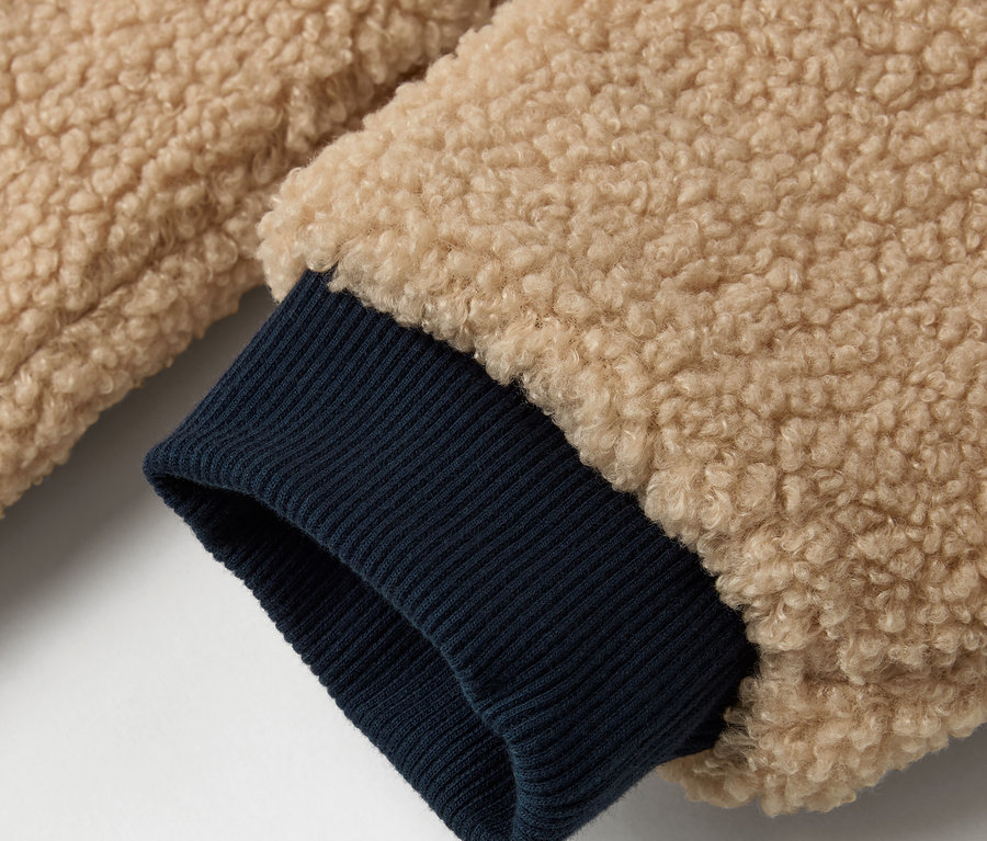 Detail einer Kinder-Wendejacke mit beigem Aussenmaterial und dunkelblauem Ärmelbund.
