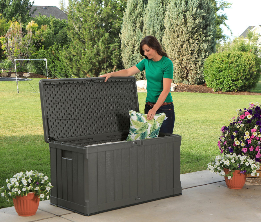 Frau legt Kissen in graue Lifetime-Kissenbox, ca. 440 l, auf Terrasse.