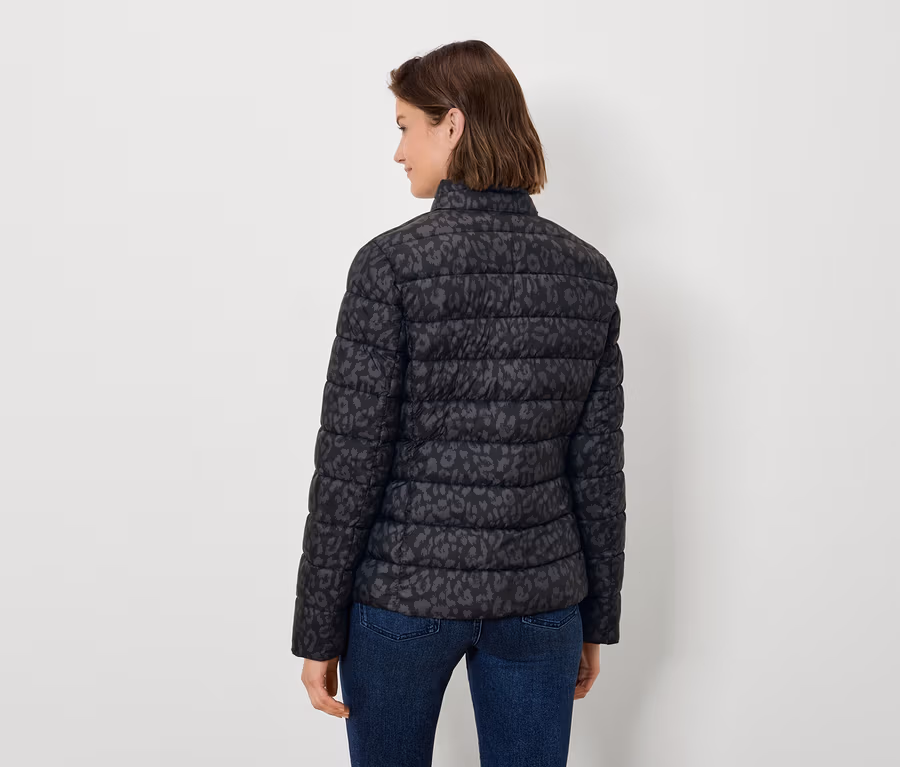 Frau von hinten trägt eine schwarze, tiermustergemusterte Steppjacke und Jeans.