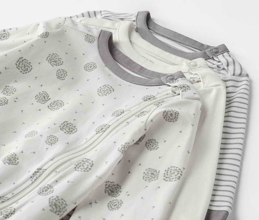 Drei Baby-Pyjamas mit Löwenzahn- und Streifenmuster.